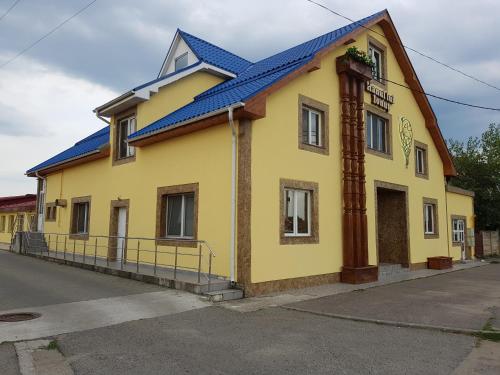 a yellow building with a blue roof on a street at Hanul Lui Ionut in Satu Mare