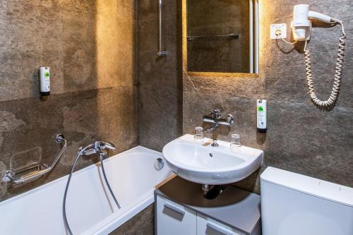 La salle de bains est pourvue d'un lavabo et d'une baignoire. dans l'établissement Drake Longchamp, à Genève