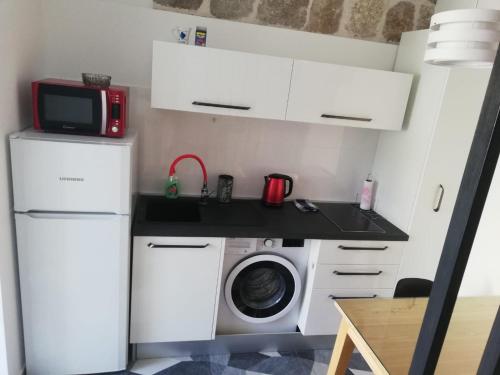 a kitchen with a washing machine and a microwave at Zanicovo beach apartment in Komiža