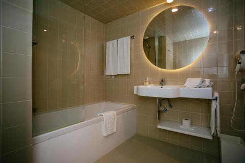 a bathroom with a tub and a sink and a mirror at Axis Vermar Conference & Beach Hotel in Póvoa de Varzim