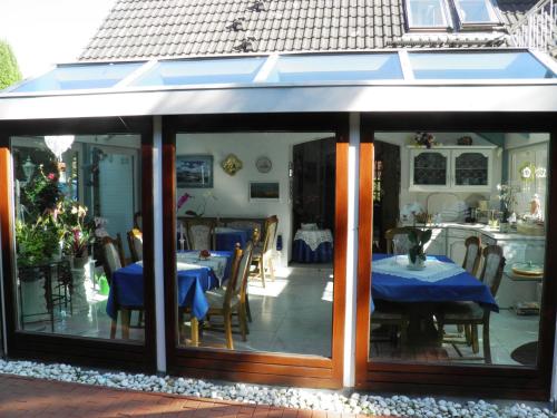 a conservatory with a table with a blue table cloth at Gästehaus Ziemann in Friedrichstadt