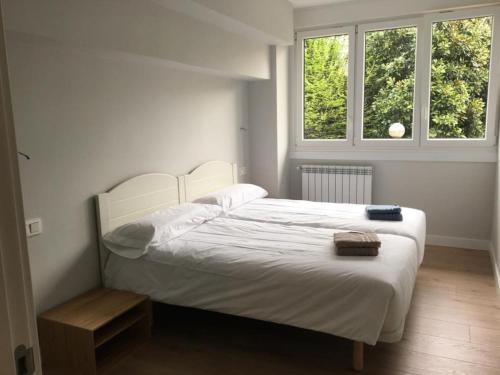1 cama blanca en un dormitorio con 2 ventanas en Irún by Basquelidays, en Irún