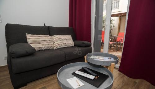 a living room with a couch and a table with remote controls at Privilège Hôtel & Apparts Eurociel Centre Comédie in Montpellier