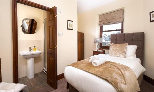 a bedroom with a bed and a sink and a mirror at Highfield House in Ambleside