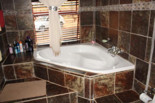 eine Badewanne im gefliesten Bad mit Fenster in der Unterkunft Copacopa Lodge and Conference Centre in Punda Maria