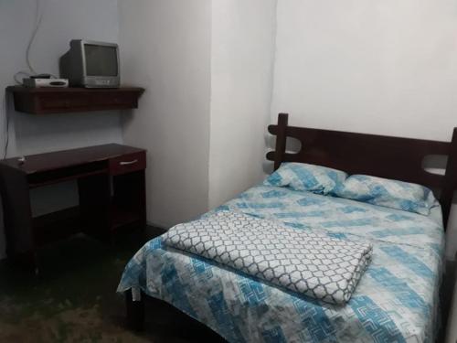 a bedroom with a bed and a desk and a tv at Pousada Mirante das Pedras in São Thomé das Letras