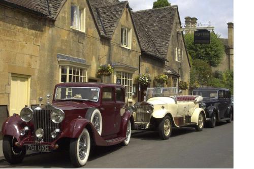 two old cars parked on the side of a street at Eight Bells Inn in Chipping Campden