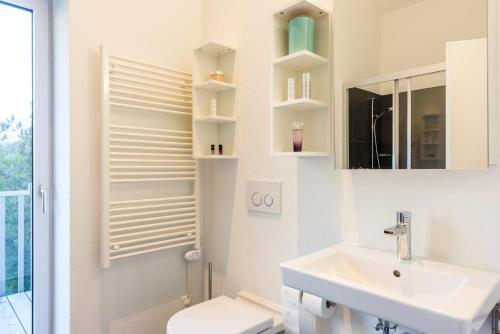 a white bathroom with a sink and a mirror at Legendär Zermatt in Zermatt