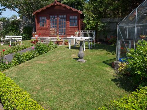 a garden with a wooden cabin and a greenhouse at Eypeleaze B&B in Bridport