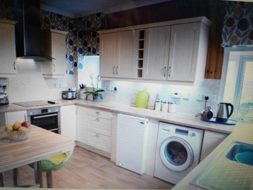 a kitchen with white cabinets and a washing machine at 27 Garenin in Carloway