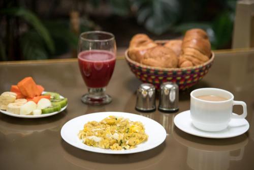 a table with two plates of food and a cup of coffee at Hotel La Orquidea in Cuenca