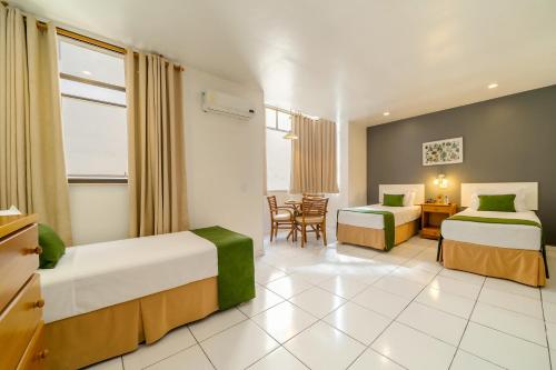 a hotel room with two beds and a table and chairs at Infinity Copacabana in Rio de Janeiro