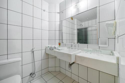 a white bathroom with two sinks and a mirror at Infinity Copacabana in Rio de Janeiro