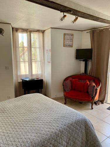 ein Schlafzimmer mit einem Bett und einem roten Stuhl in der Unterkunft Appartement de la Duchesse de Dino in Valençay