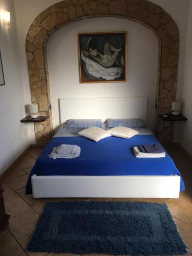 um quarto com uma cama azul e uma parede de pedra em Suite Margarita em Mazara del Vallo