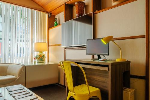 a room with a desk with a computer and a yellow chair at Infinity Copacabana in Rio de Janeiro