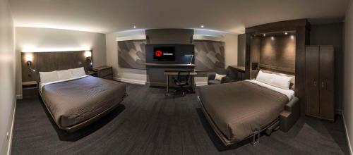 a hotel room with two beds and a desk at Hôtel & Suites Normandin Lévis in Lévis