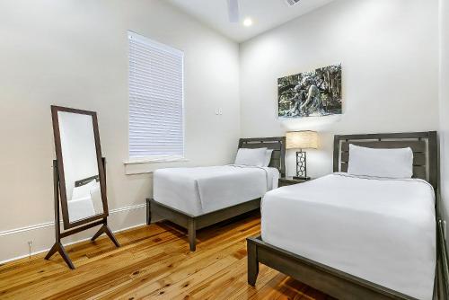 a bedroom with two beds and a mirror in it at Fabulous Cottages with City Views in New Orleans