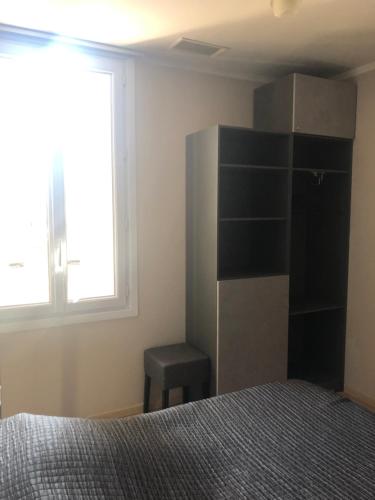 a bedroom with a bed and a stool next to a window at Hôtel Le Lys d'Or in Vauvert