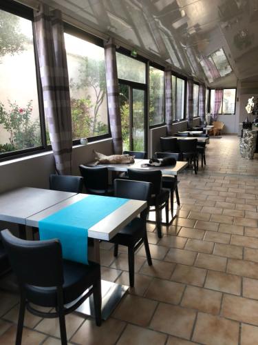 a row of tables and chairs in a room with windows at Hôtel Le Lys d'Or in Vauvert