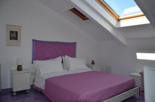 a bedroom with a bed with purple sheets and a window at La Soffitta Sul Mare in Vietri sul Mare