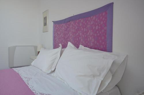 a bed with white pillows and a purple headboard at La Soffitta Sul Mare in Vietri sul Mare