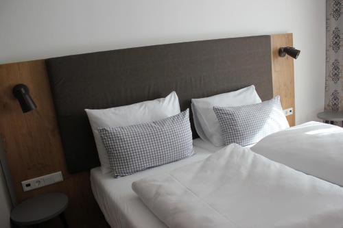 Hotel Brunnthal في برونتال: غرفة نوم بسريرين مع شراشف ووسائد بيضاء