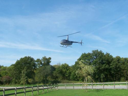 a helicopter flying over a field with a fence at Hotel Les Mignees in Barvaux