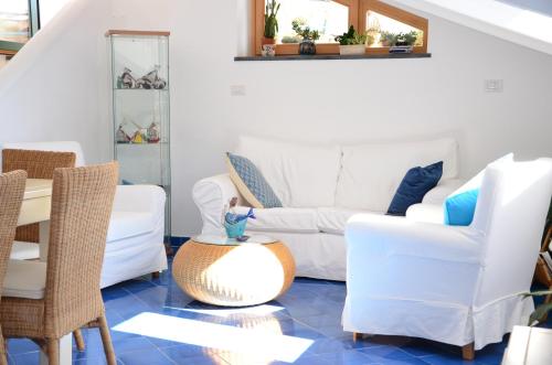 a living room with white furniture and a blue tile floor at La Soffitta Sul Mare in Vietri sul Mare