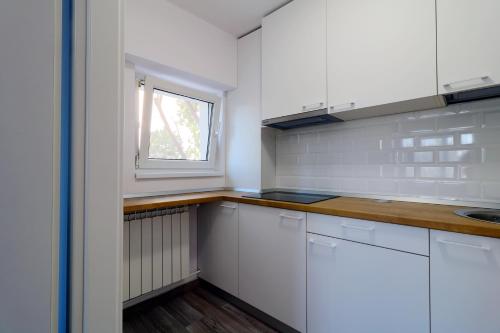 una cocina con armarios blancos y una ventana en Luxury Olimpia Studio in Bucharest, with Netflix, en Bucarest