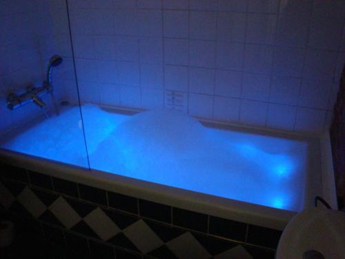 a blue tub filled with blue water in a bathroom at " Chimay B & B " - ptits déj gourmands proposés in Chimay