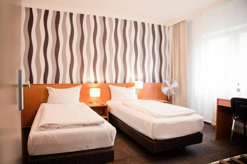 a hotel room with two beds and a striped wall at Les Nations in Berlin