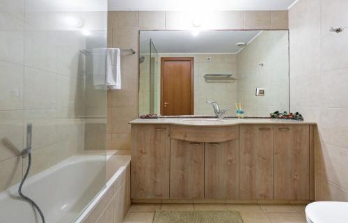 een badkamer met een bad, een wastafel en een spiegel bij Lagoon Water Front Suite in Herzliyya B