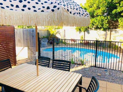 a table with an umbrella and chairs next to a pool at The Lazy Llama in Evans Head