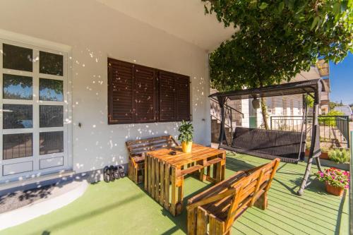 a patio with two benches and a table on a house at Apartments Barbir in Ploče