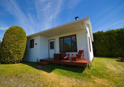 a small white house with two chairs and a table at Domaine Frais Air in La Malbaie