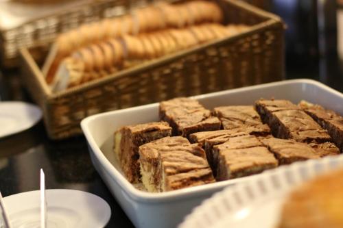a tray of brownies sitting on a table with baskets of bread at Samba Itaboraí in Itaboraí