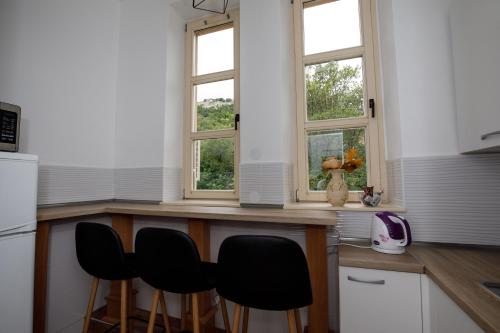 uma cozinha com três janelas e um balcão com cadeiras em Prenoćište Kastel em Knin