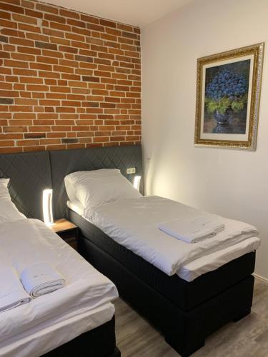 twee bedden in een kamer met een bakstenen muur bij Haus 8 in Lübeck