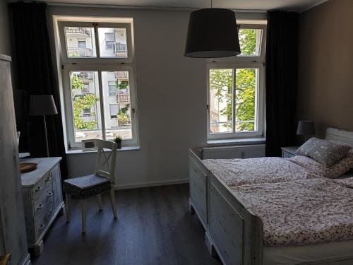 ein Schlafzimmer mit einem Bett und einem Schreibtisch und zwei Fenstern in der Unterkunft Ferienwohnung Busch in Leipzig