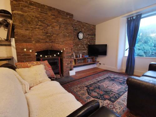 a living room with a couch and a fireplace at THE OLD RECTORY KIRKULLEN LOFT APARTMENT in Jacobstow 10 mins to Widemouth bay and Crackington Haven,15 mins Bude,20 mins tintagel, 27 mins Port Issac in Jacobstow