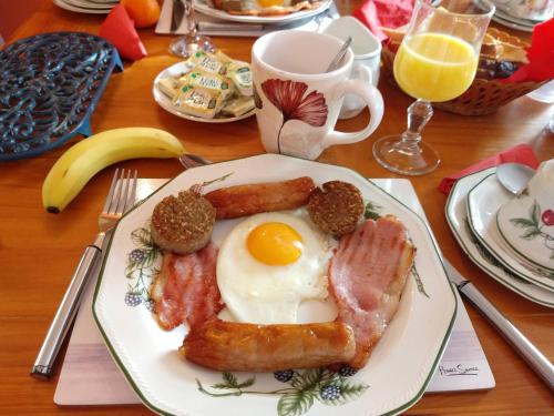 ein Frühstücksteller mit Eiern, Speck und Wurst in der Unterkunft Grannagh Castle House in Waterford