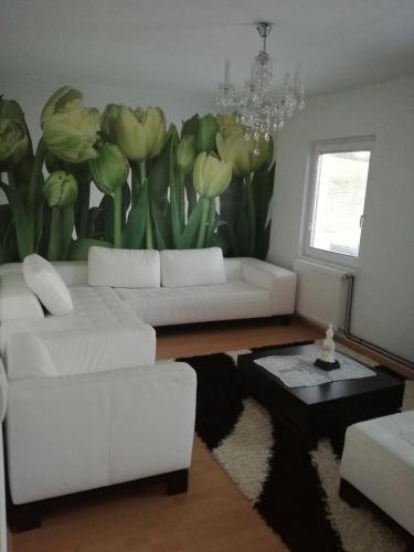 a living room with white furniture and a painting of flowers at Vila Boba Bor in Zlot