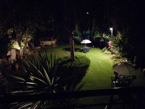 a garden at night with tables and umbrellas at Niki Thalia Viros Apartment 2 in Kastanéa
