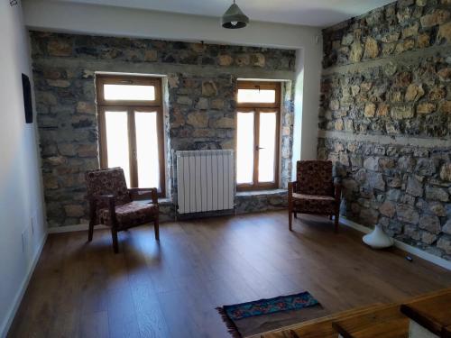 a living room with two chairs and a stone wall at Vila 43 Lin in Lin
