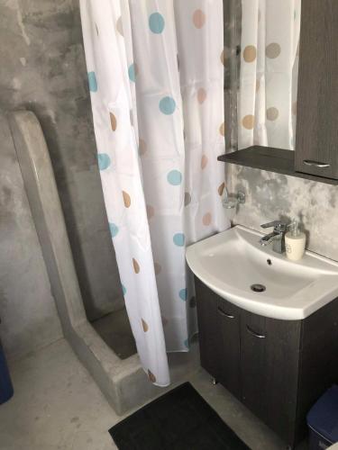 a bathroom with a shower curtain and a sink at Cycladic house in Kithnos