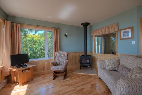 a living room with a couch and a tv at Domaine Frais Air in La Malbaie
