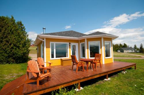 a house with a deck with chairs and a table at Domaine Frais Air in La Malbaie