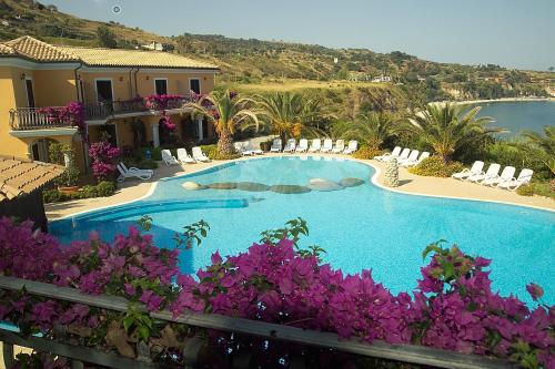 - une piscine avec des fleurs violettes en face d'une maison dans l'établissement Villaggio Hotel Lido San Giuseppe, à Briatico