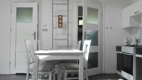 une cuisine avec une table blanche et deux chaises dans l'établissement Domek nad Jeziorem, à Zyndaki